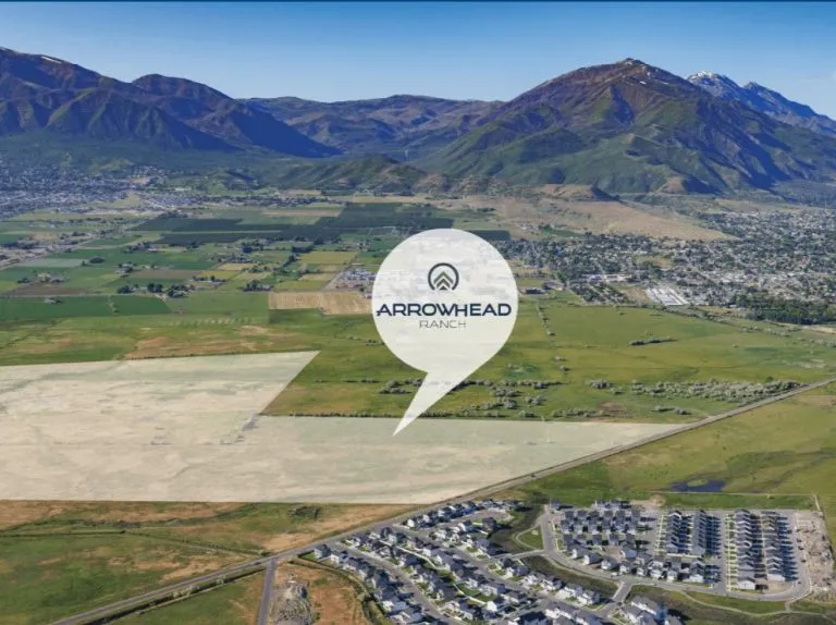 Aerial view of a green valley with mountains in the background; Arrowhead Ranch is marked with a location pin, showcasing homes in Utah and a residential neighborhood in the lower right corner.