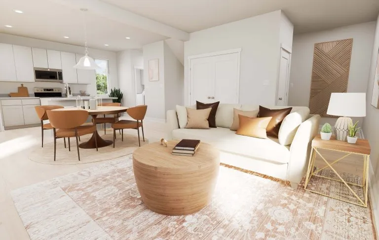 A bright, modern living room in homes in Utah with a cream sofa, brown and beige pillows, a wooden coffee table, and a dining area with brown chairs. Light walls, a patterned rug, and natural light from a window complete the space.