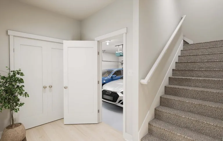 A clean, modern hallway with beige walls and carpeted stairs, a potted plant, and a white double-door closet—features often found in homes in Utah. An open door reveals a garage with a blue car parked inside.