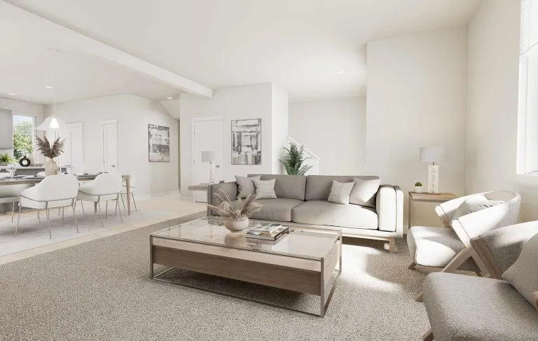 A bright, modern living room with neutral tones features a gray sofa, two armchairs, and a glass coffee table with decor—reflecting the airy style found in many homes in Utah. Sunlight streams through large windows, creating a welcoming atmosphere.