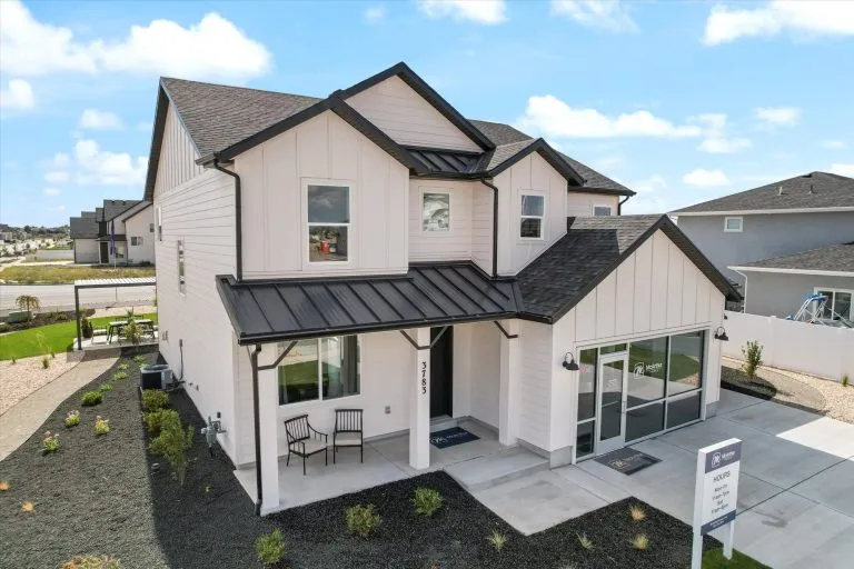 Aerial view of a two-story McArthur Homes model at 3783 with white farmhouse siding, covered front porch, and desert-style landscaping.