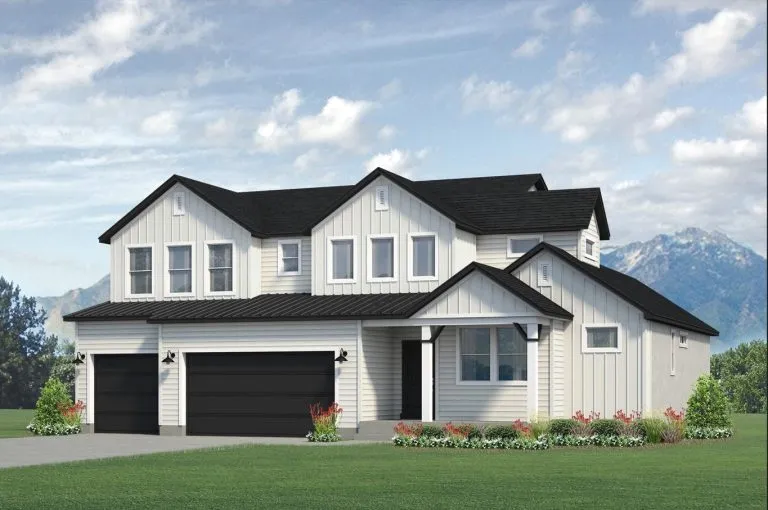 A modern two-story white house with black trim and a three-car garage sits on a green lawn with flower beds in front. Mountains and a partly cloudy sky are visible in the background.